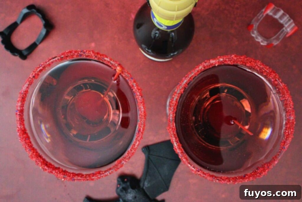 Crimson Fang Nectar 8 overhead view of two vampire kiss cocktails with red sugar rim and cherry garnish on a red counter