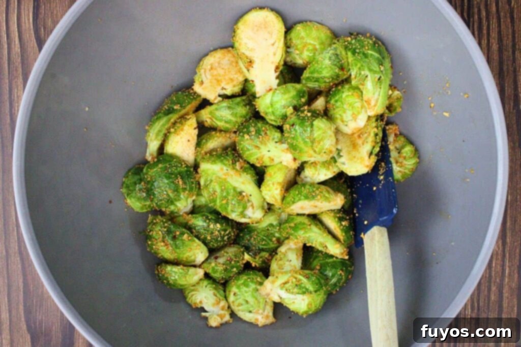 Tossing halved brussel sprouts with olive oil and maple seasoning in a bowl