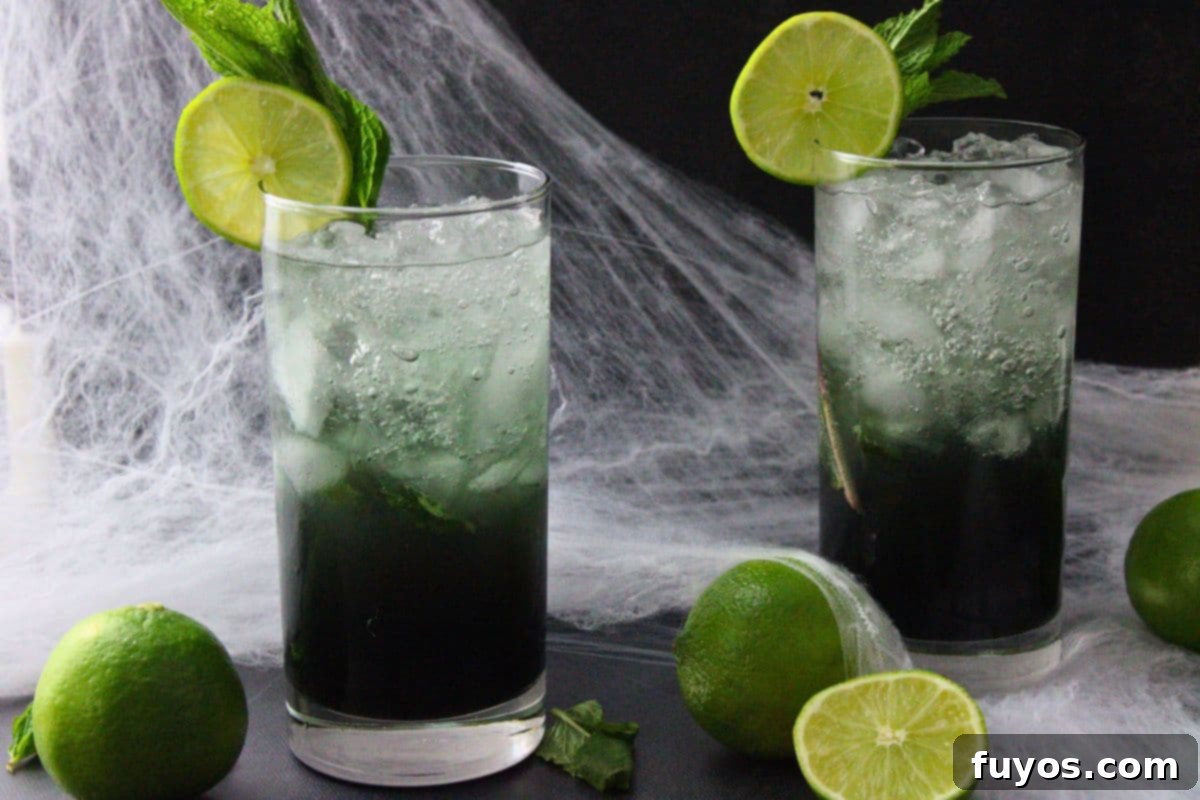 two black mojito cocktails in front of spiderwebs with fresh limes