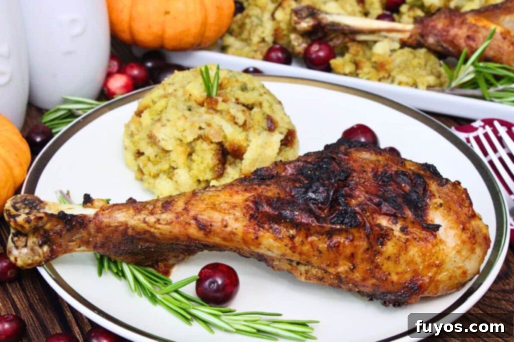 juicy and crispy air fryer turkey leg on a plate with stuffing, cranberries, and a sprig of rosemary