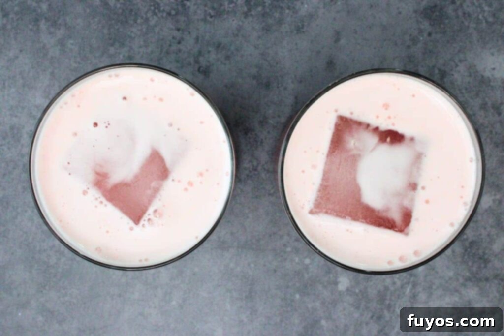 strain cranberry vodka sour into glass with ice