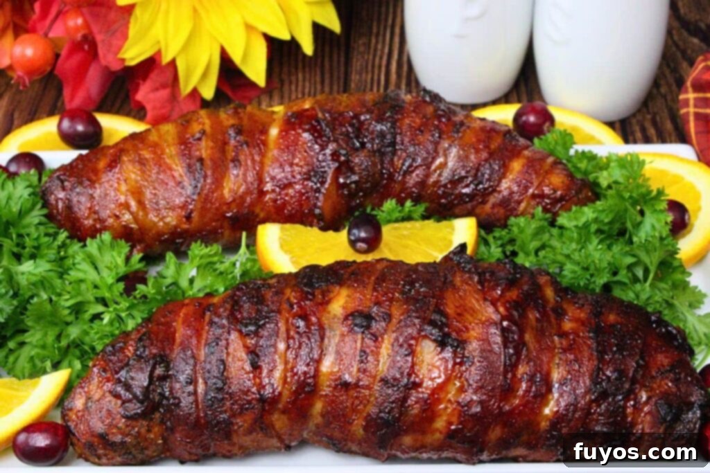 Easy Air Fryer BBQ Bacon Wrapped Turkey Tenderloin 3 two uncut bacon wrapped turkey tenderloins on a white platter with fresh garnishes
