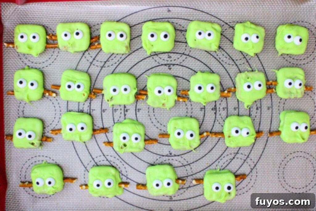 add candy eyes and pretzel rod pieces to chocolate pretzels