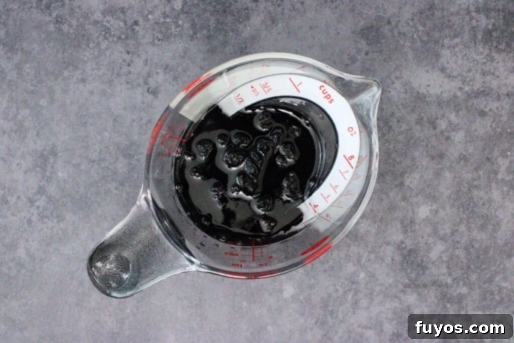 Dried blueberries soaking in orange liqueur in a small bowl, part of the microwave cranberry sauce recipe preparation