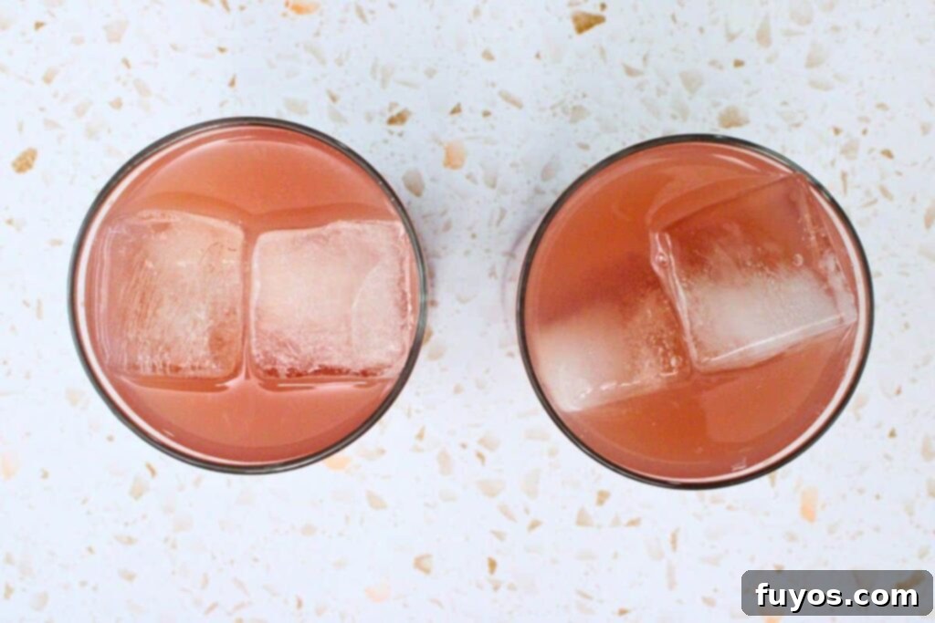 Adding vodka, cranberry juice, and grapefruit juice to a glass filled with ice