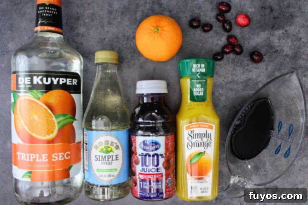 A collection of ingredients laid out, including red wine, triple sec, cranberry juice, orange juice, fresh cranberries, and orange slices, ready to be transformed into cranberry sangria.