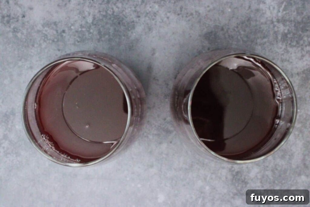 The initial step of making cranberry sangria, showing red wine, cranberry juice, orange juice, triple sec, and simple syrup being added to a wine glass and gently stirred.