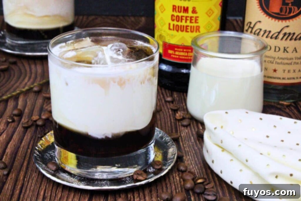 white russian cocktail on a silver coaster in front of cream and liquor bottles