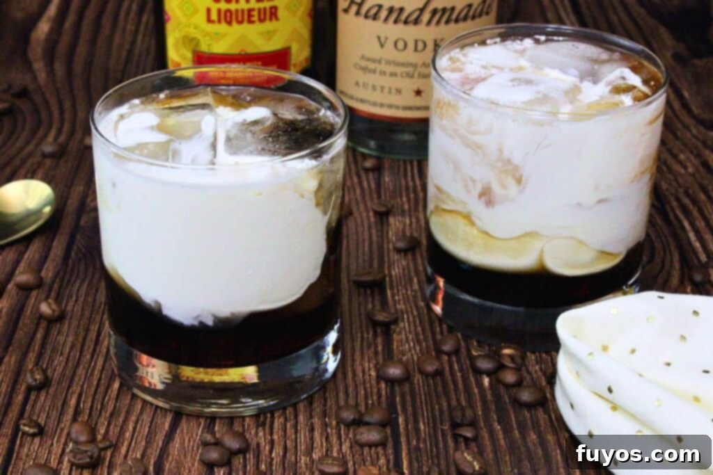 two white russian cocktails on a wooden counter with coffee beans surrounding