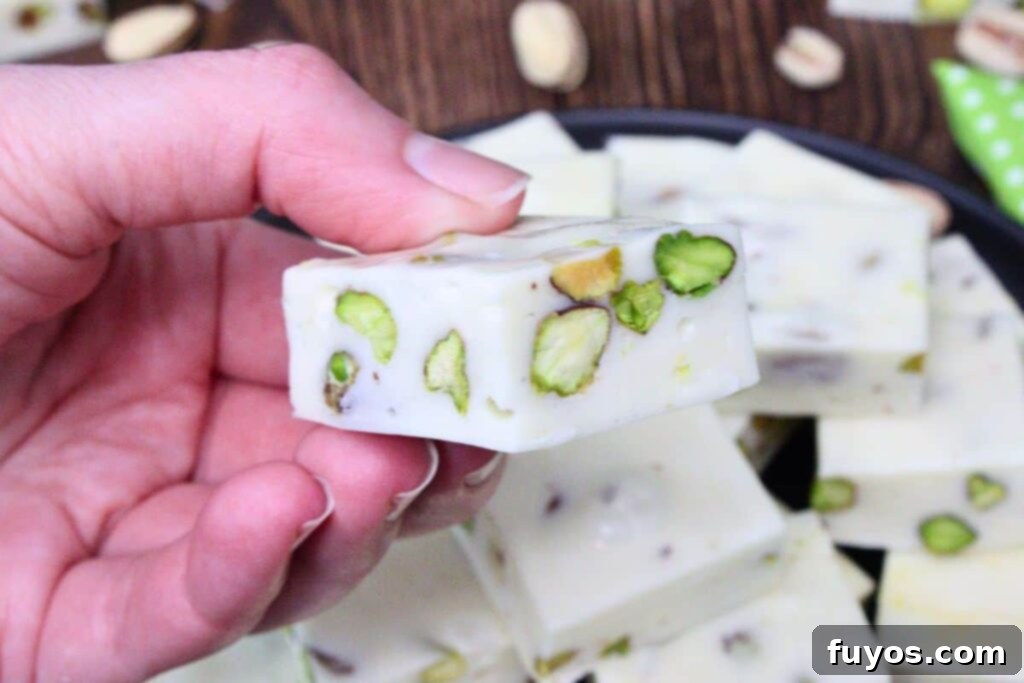 A slice of homemade pistachio nougat, showcasing its chewy and nutty texture