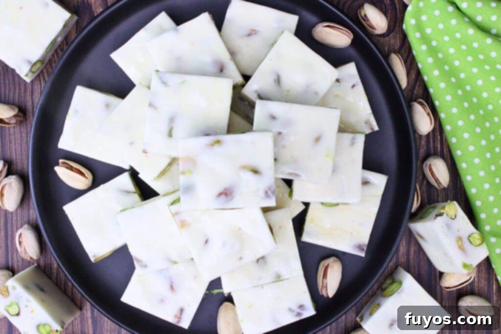 Overhead view of homemade pistachio nougat squares on a black plate