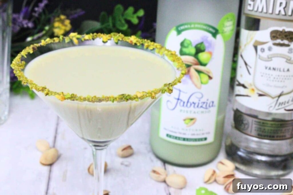 closeup of pistachio martini showing nut rimmed glass in front of liquor bottles