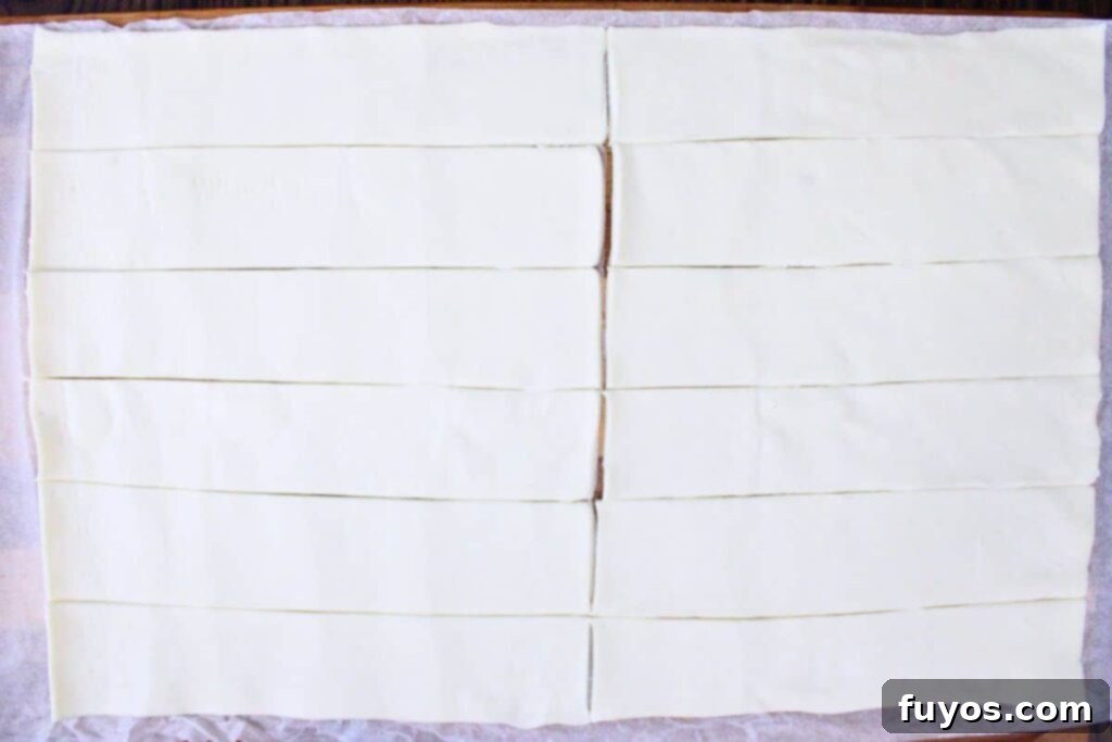Roll out puff pastry dough and cut into even strips for apple roses