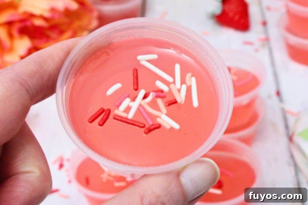 Holding up a Pink Whitney Jello shot showing off sprinkles