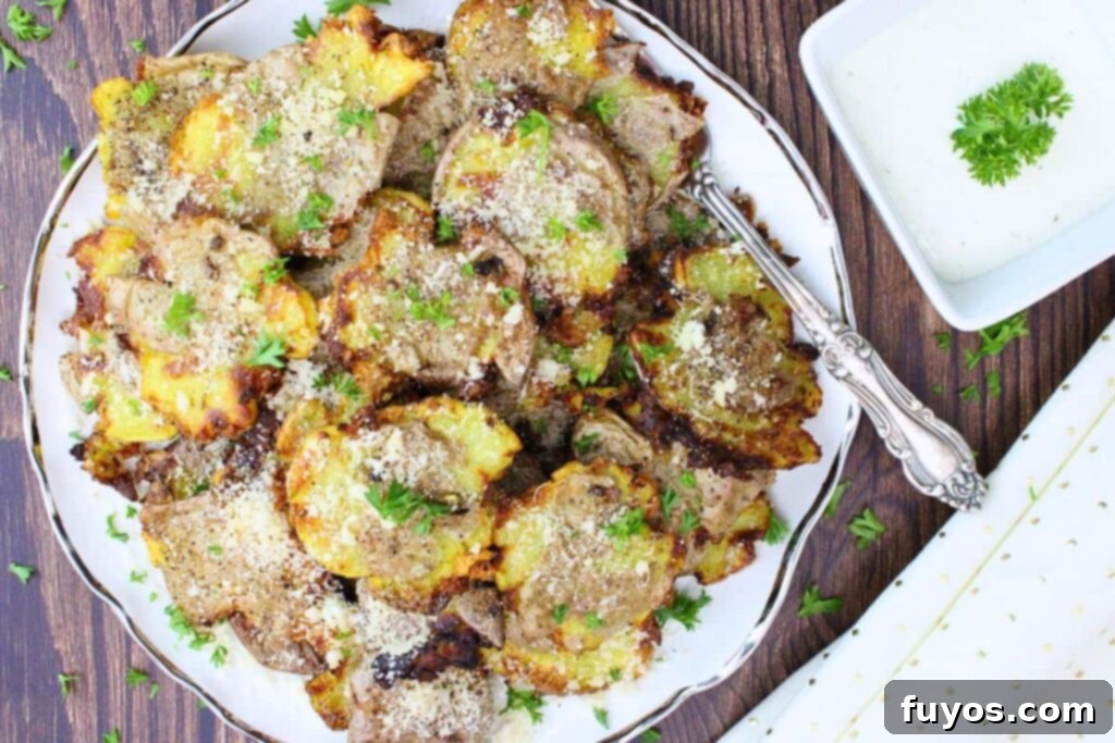 Air Fryer Smashed Potatoes with Garlic Parmesan Goodness 8 Overhead view of air fryer smashed potatoes with parmesan cheese on a plate next to a small dish of ranch