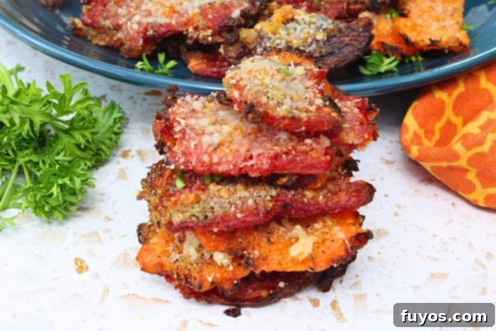 air fryer smashed carrots with garlic parmesan seasoning stacked on top of each other in front of blue plate