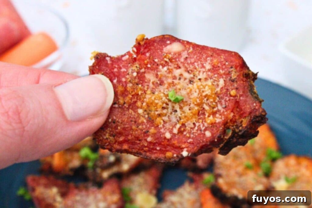 holding up an air fryer smashed carrot with garlic parmesan seasoning