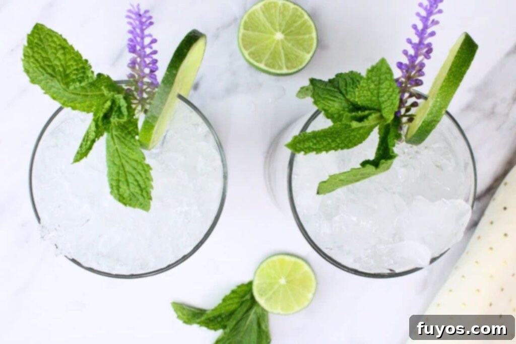 Lavender Mojito: Aromatic Spring Refresher 7 Overhead view of two lavender mojito drinks with crushed ice, lime, and mint on a white marble counter, emphasizing the drink's elegance.