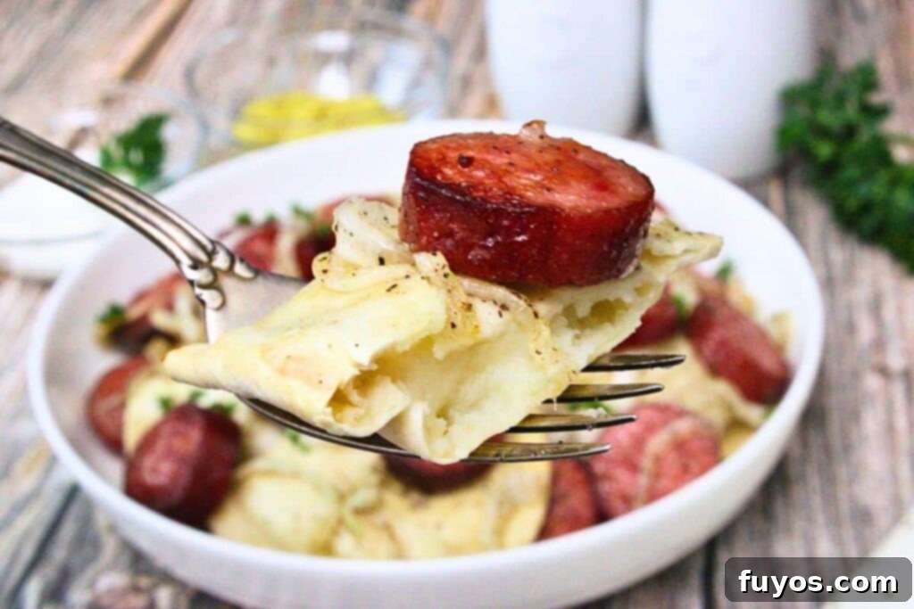 Holding up a fork with half a pierogi and piece of air fried kielbasa on it